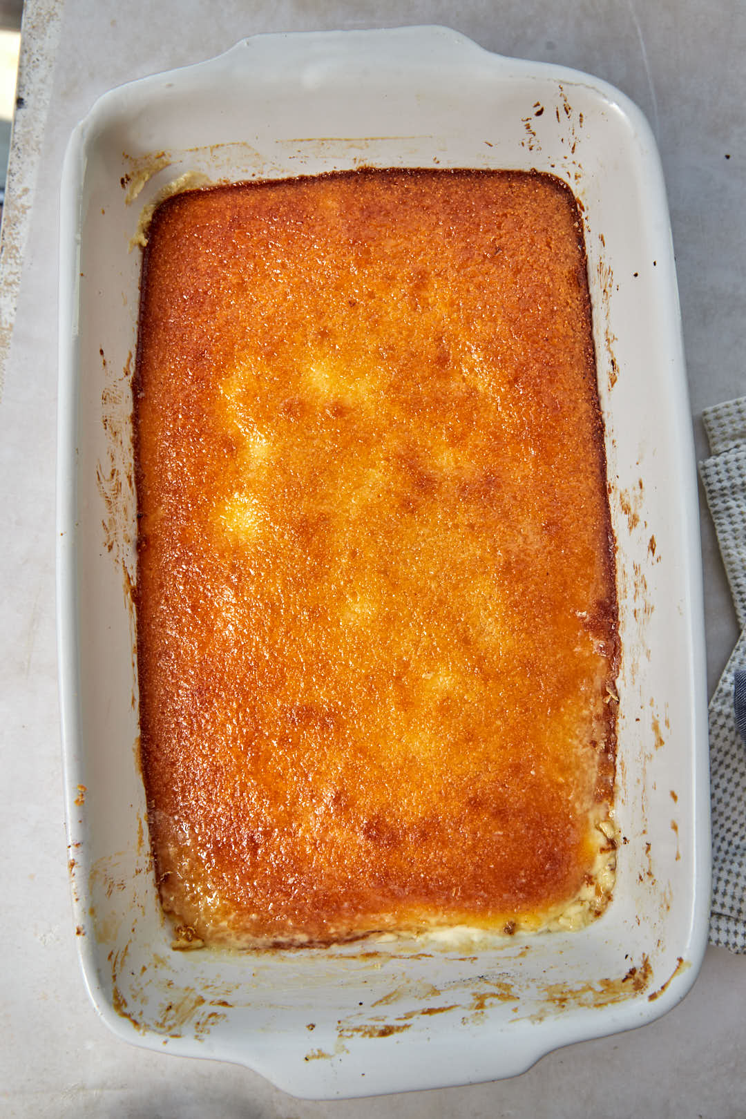 baked golden brown basbousa in a white baking dish.