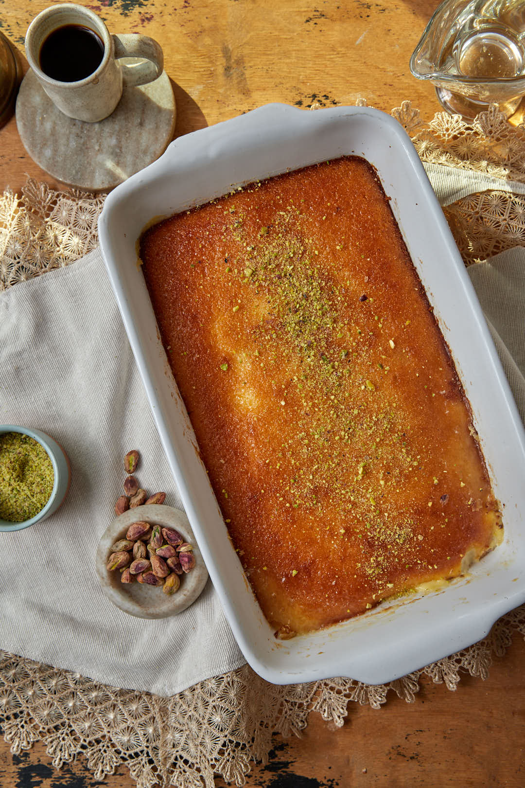 full sized pan of cream stuffed basbousa with pistachios on the table.
