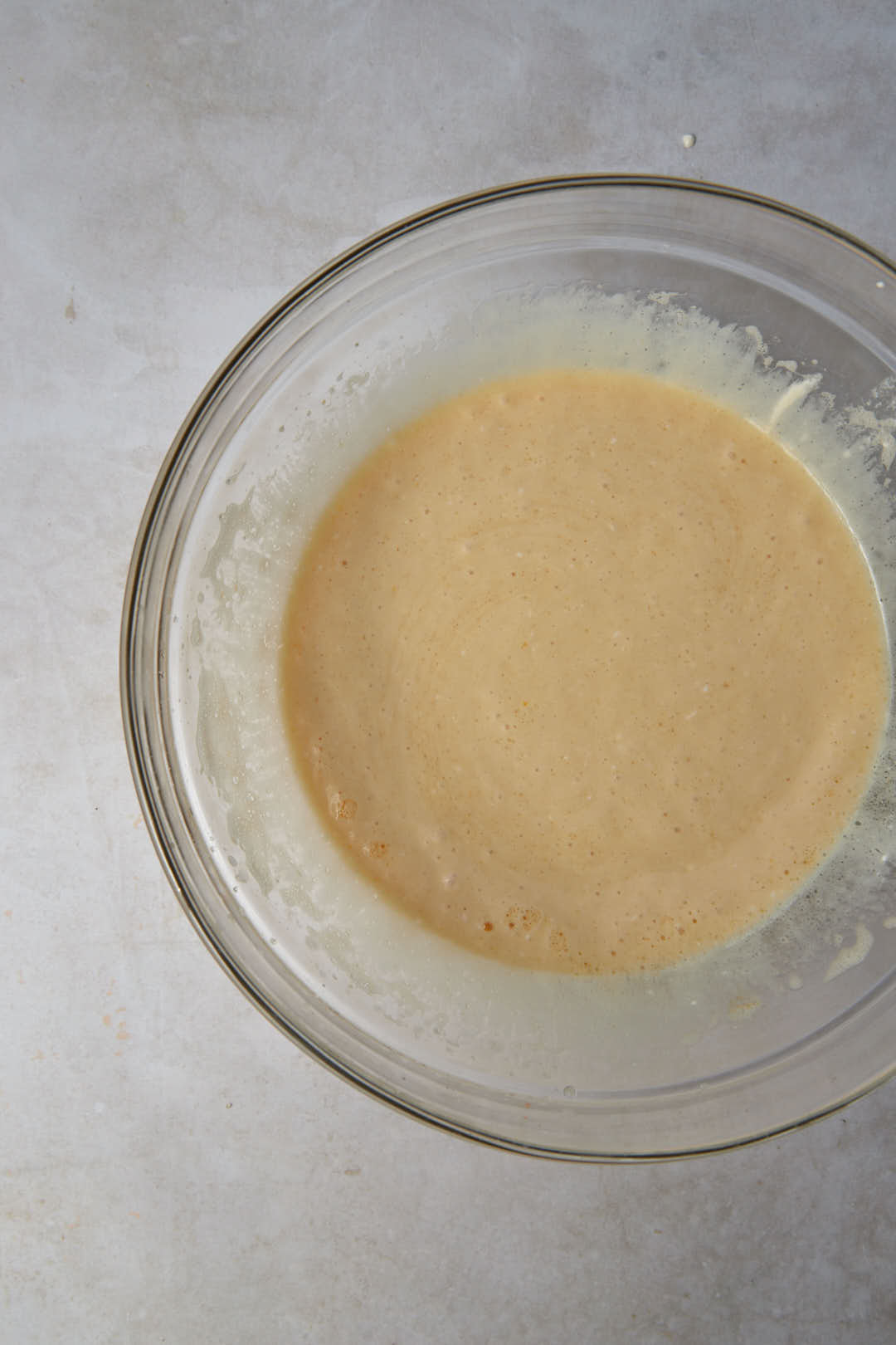 beaten eggs, sugar, yogurt, and cream in a glass bowl.