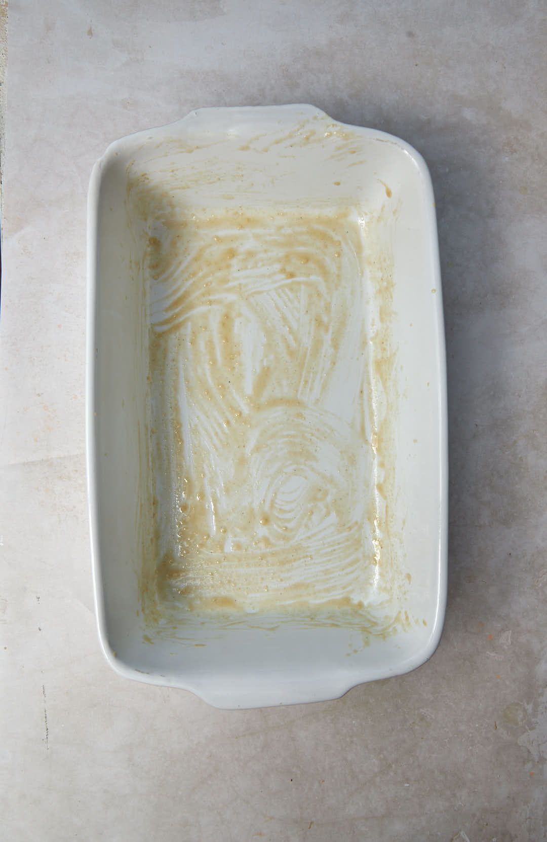 tahini greased white baking dish on a marble background.