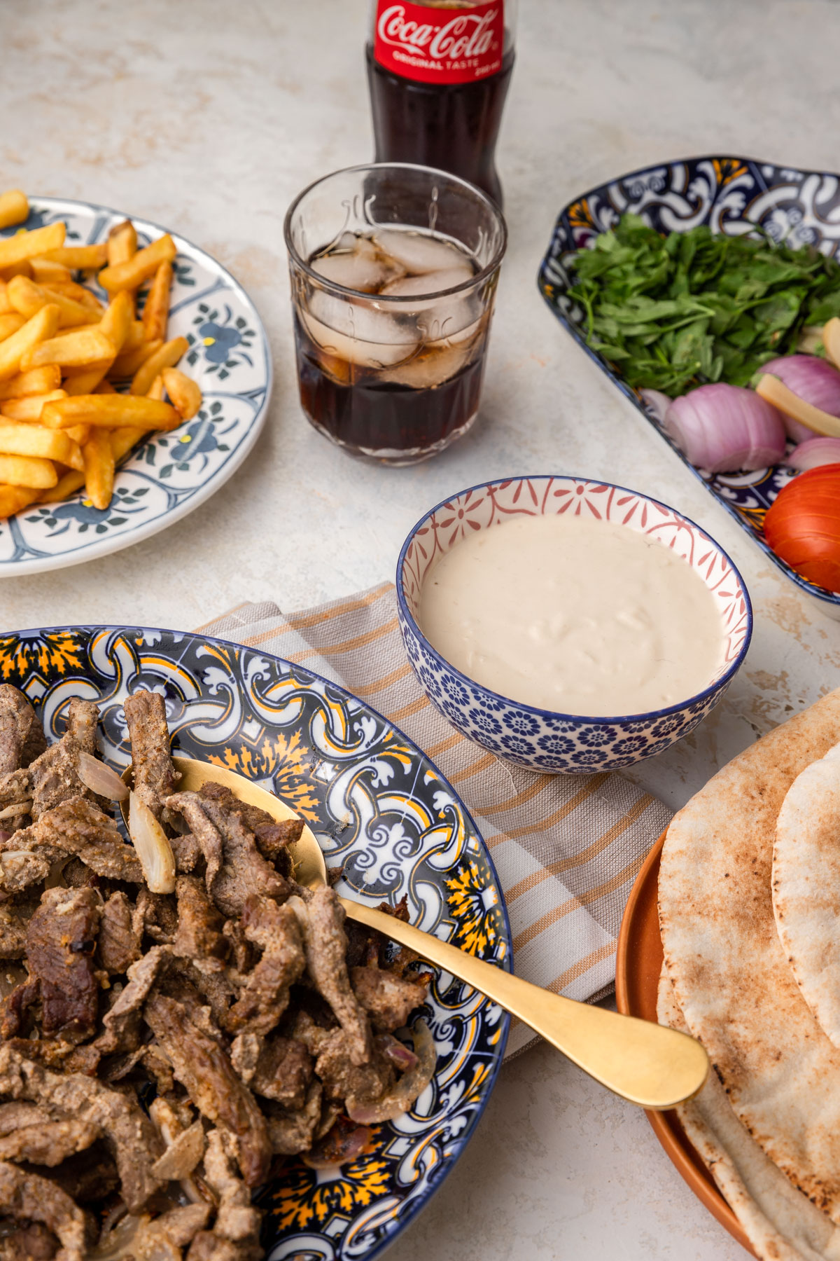 shawarma on a plate surrounded by bread and vegetables. 