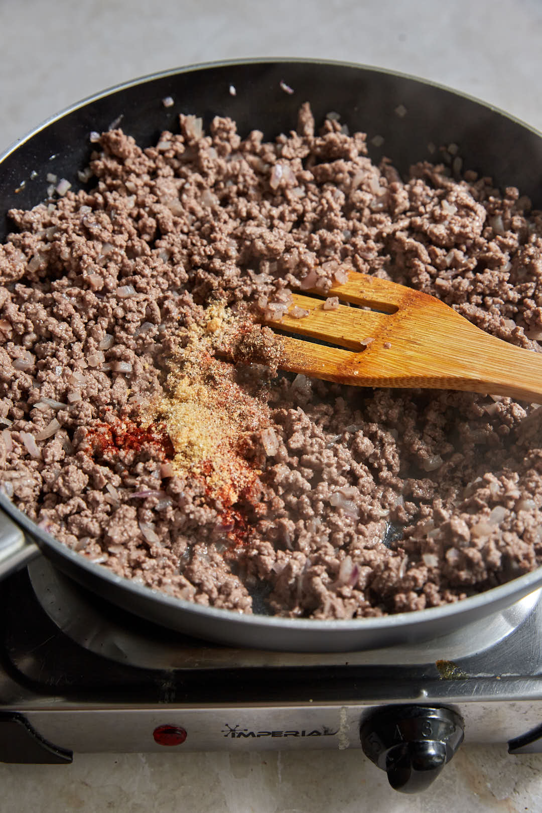 seasoning added to ground beef in a skillet.