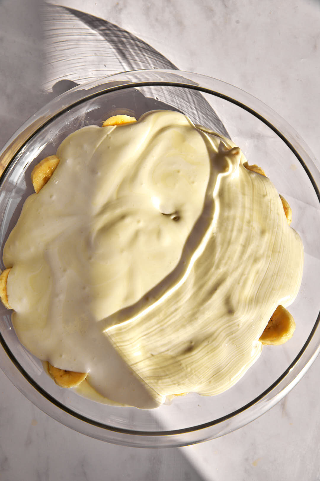 pudding mix covering sliced bananas in a glass bowl.