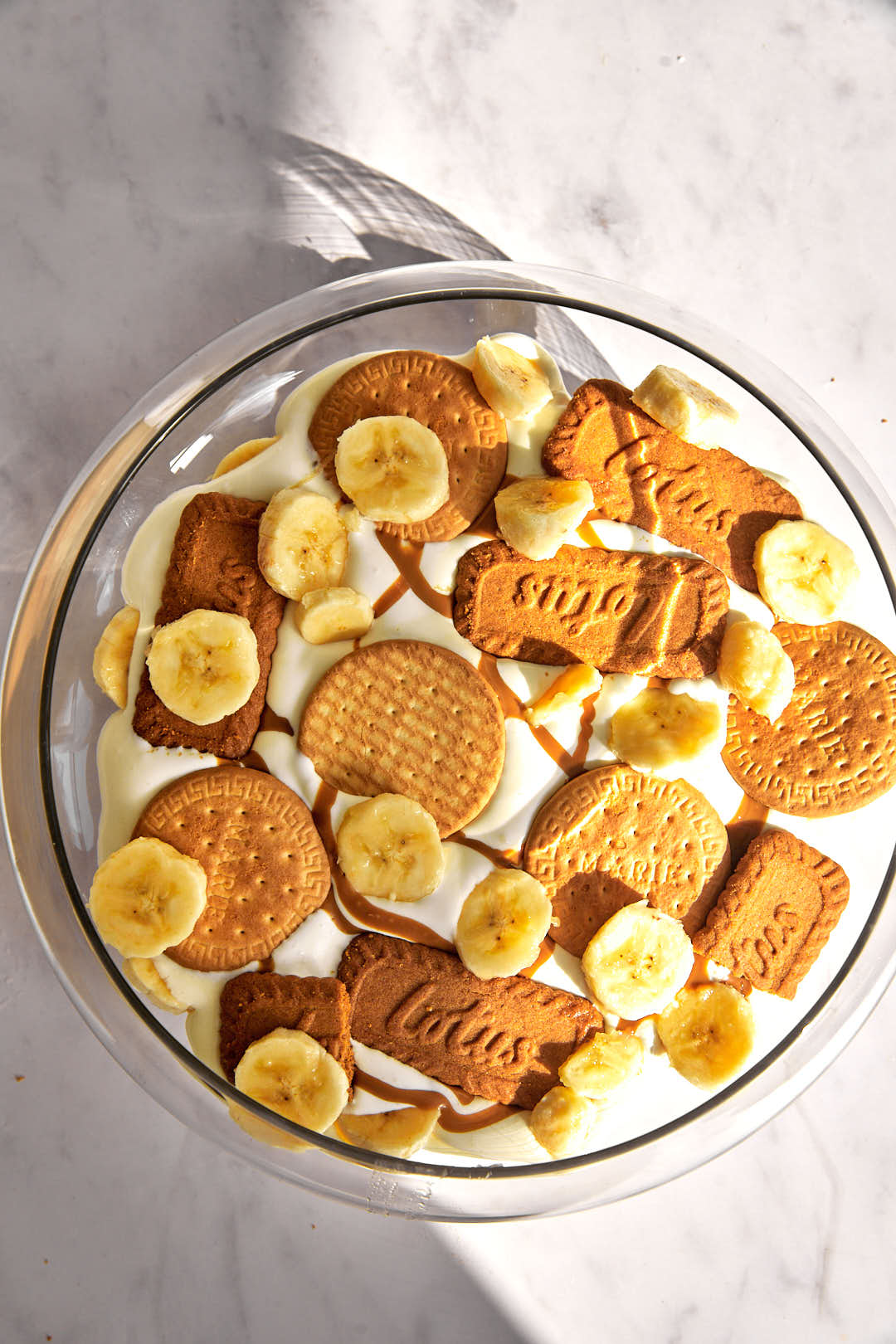 biscuits and banana slices on pudding mix in a glass bowl