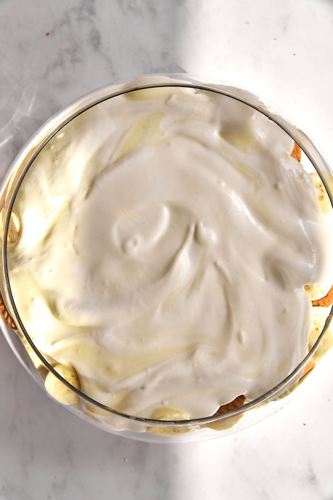 pudding mixture spread over banana slices in a glass bowl.