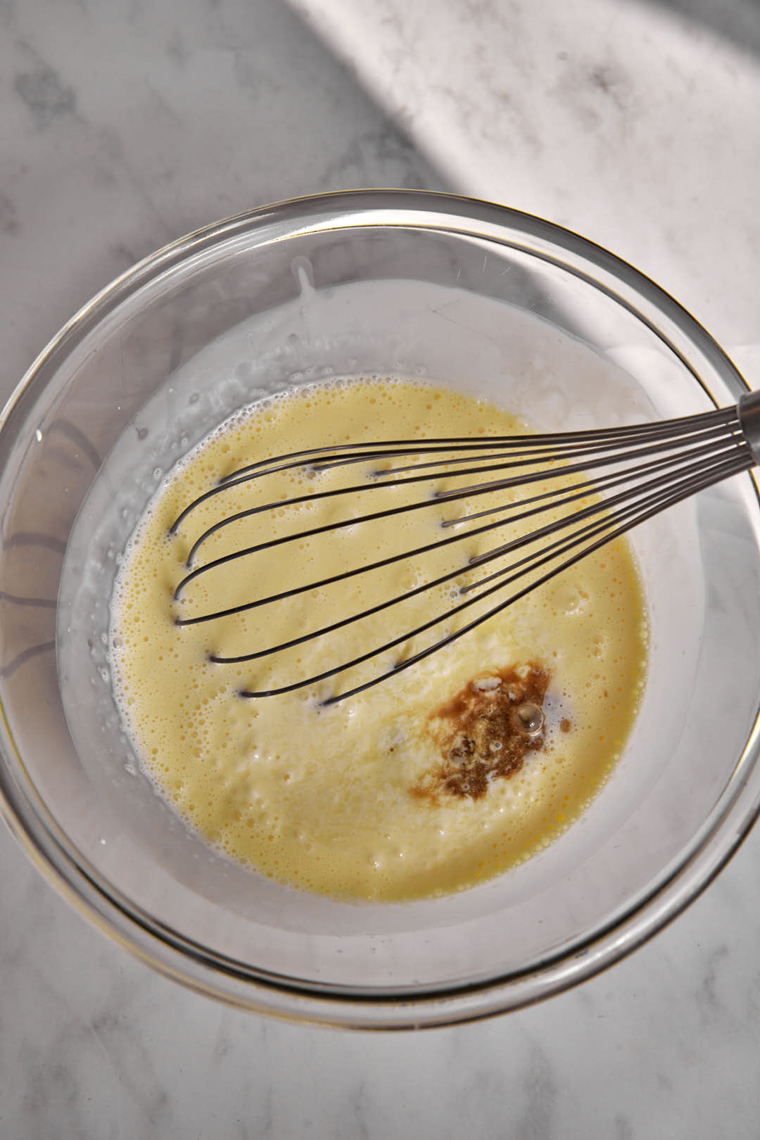 Condensed milk, lemon juice and vanilla extract in a glass bowl with a whisk.