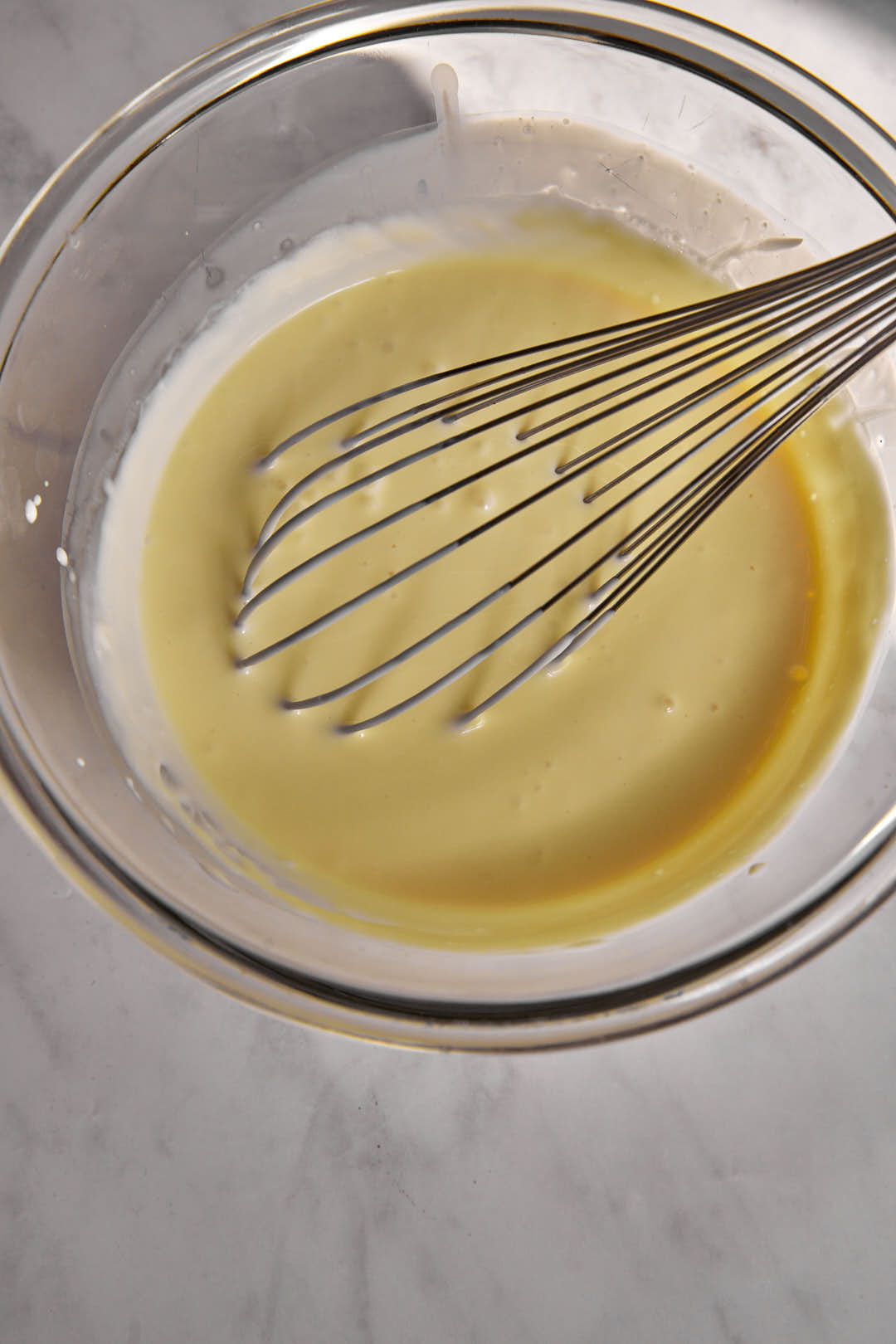 beaten condensed millk in a glass bowl.