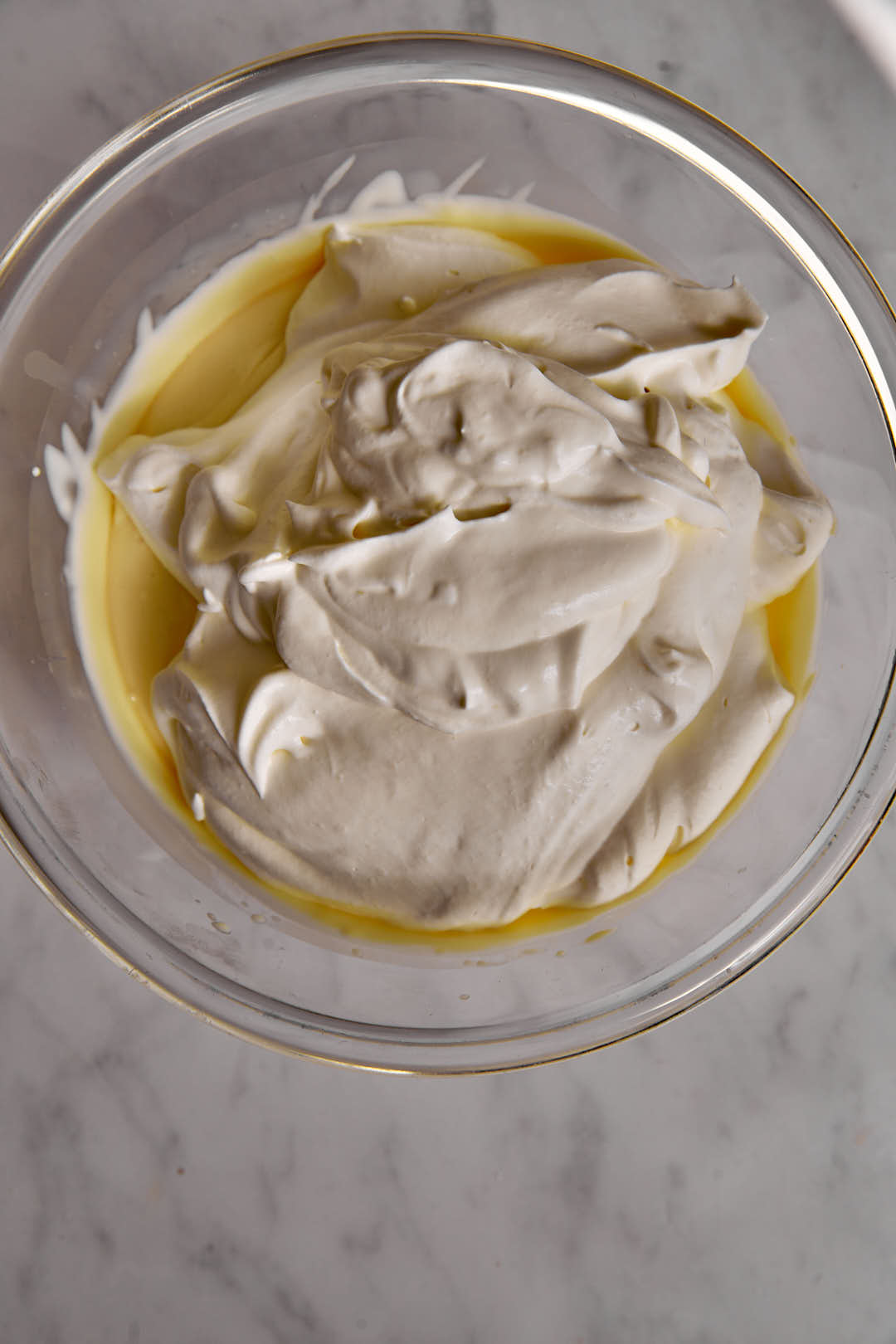 heavy crem added to condensed milk in a glass bowl.,