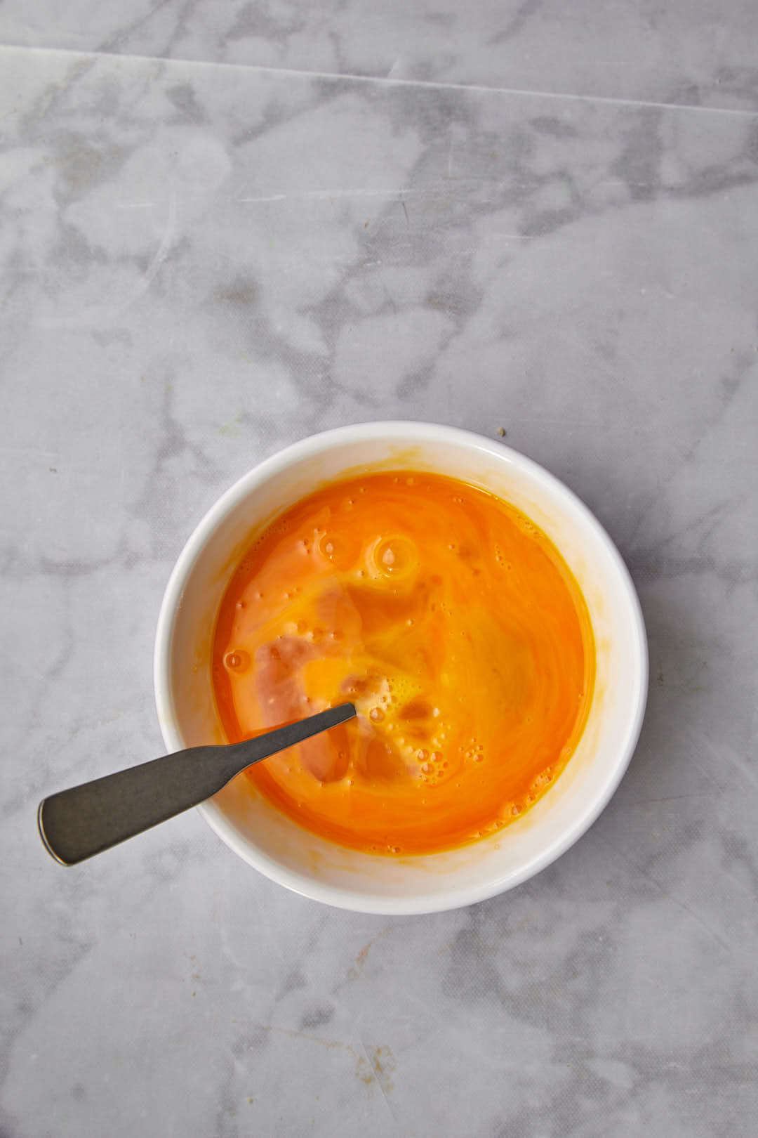 eggs and sugar beaten together in a small white bowl.