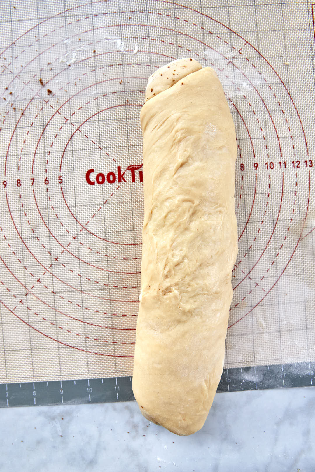 log of cinnamon roll dough on a silicone sheet.