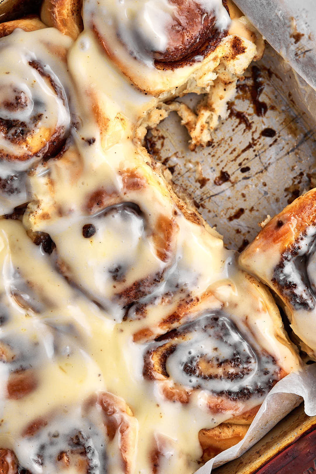 a tray of brown butter cinnamon rolls with one roll taken out.
