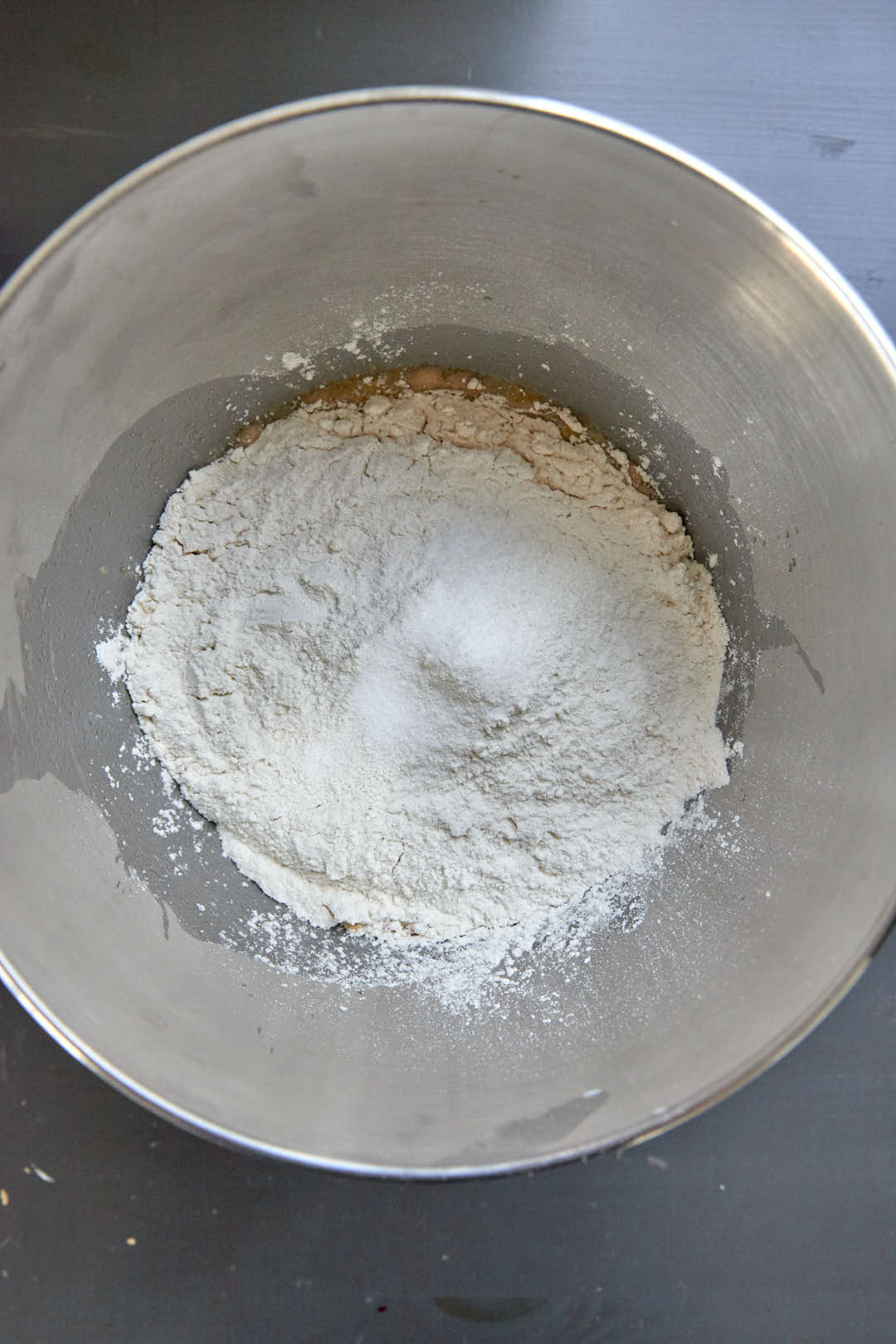 flour added to wet ingredients in a stand mixer bowl.