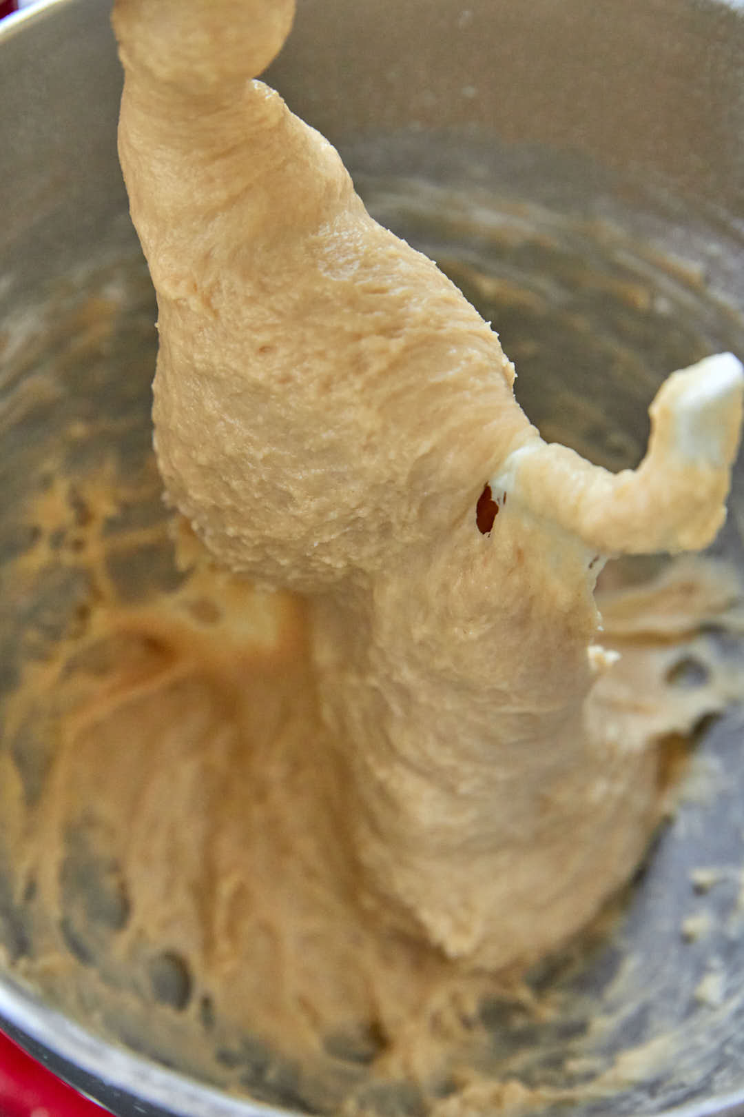 Stand mixer with a dough hook with cinnamon roll dough being formed.