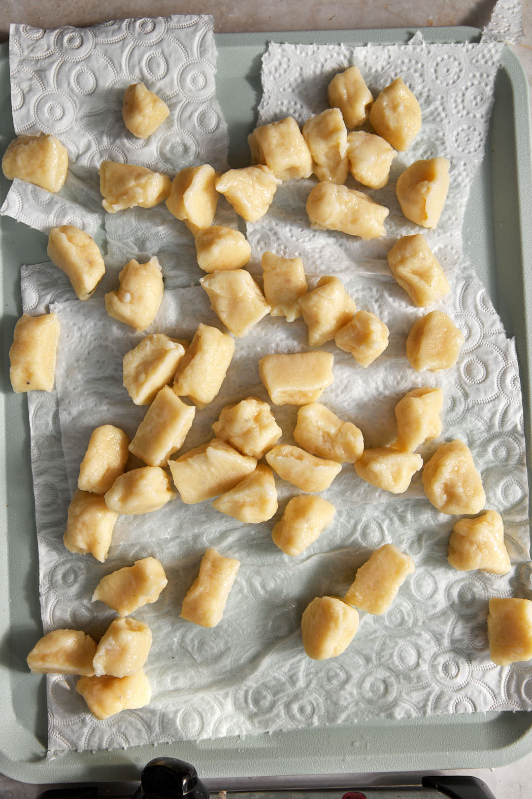 gnocchi being dried on a paper towel lined tray.
