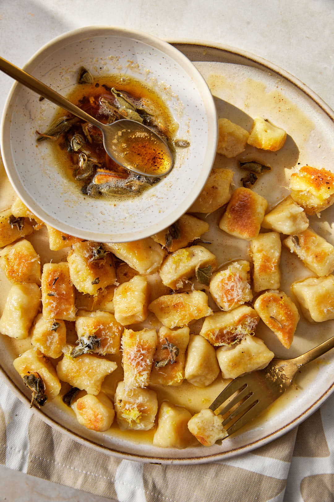 brown butter gnocchi with a small bowl of brown butter sage on the plate.