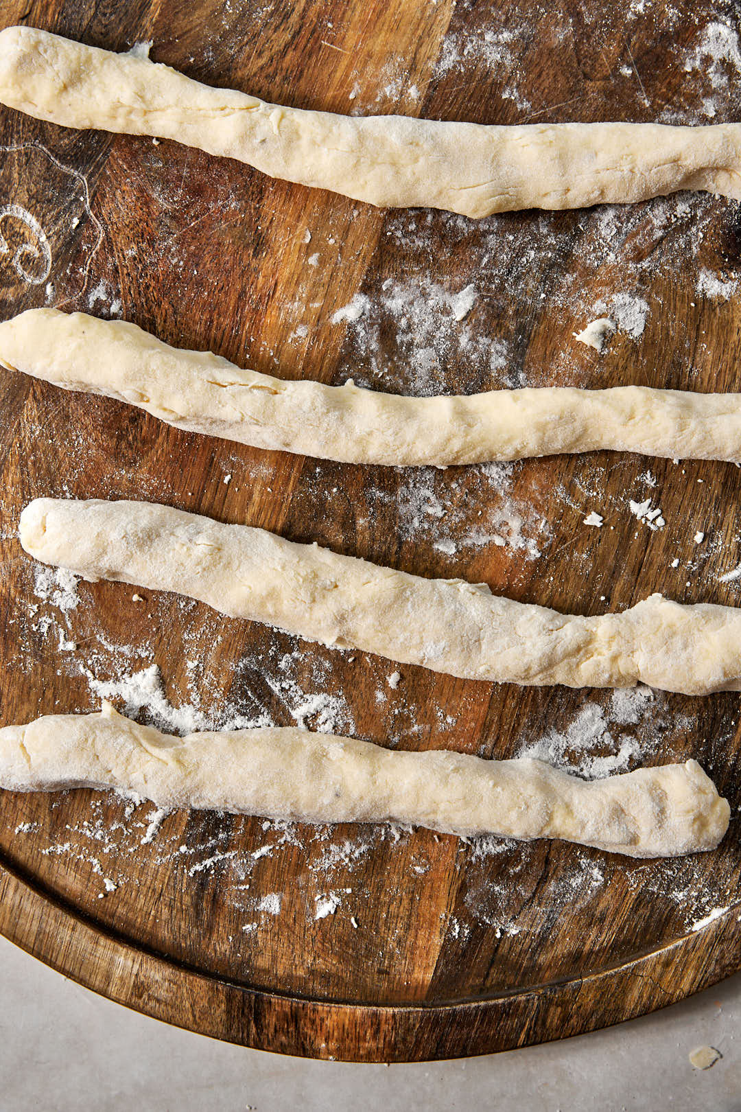 small ropes of gnocchi on a floured wooden surface.