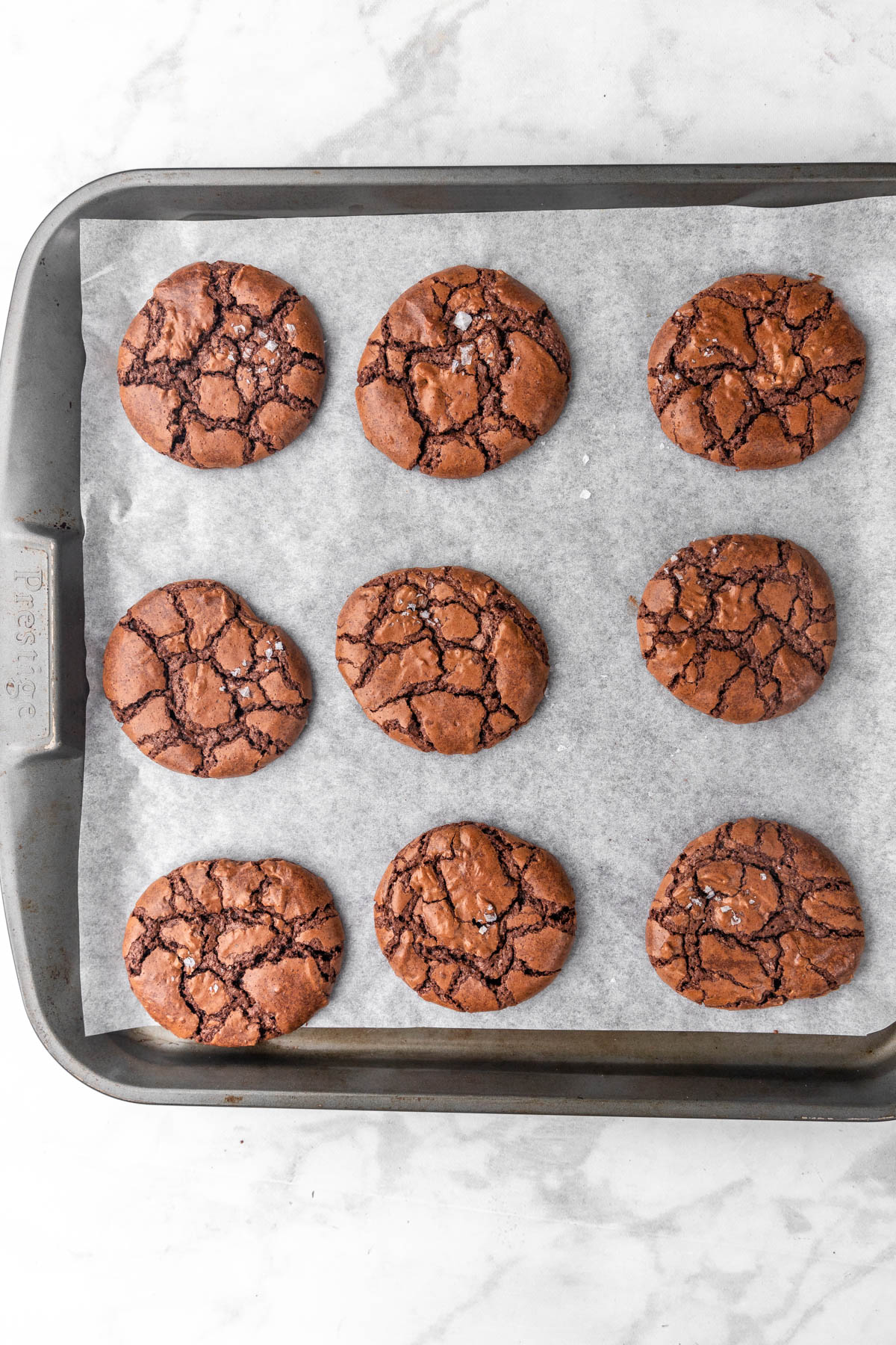 baked brownie crinkle cookies on parchment paper lined baking sheet.