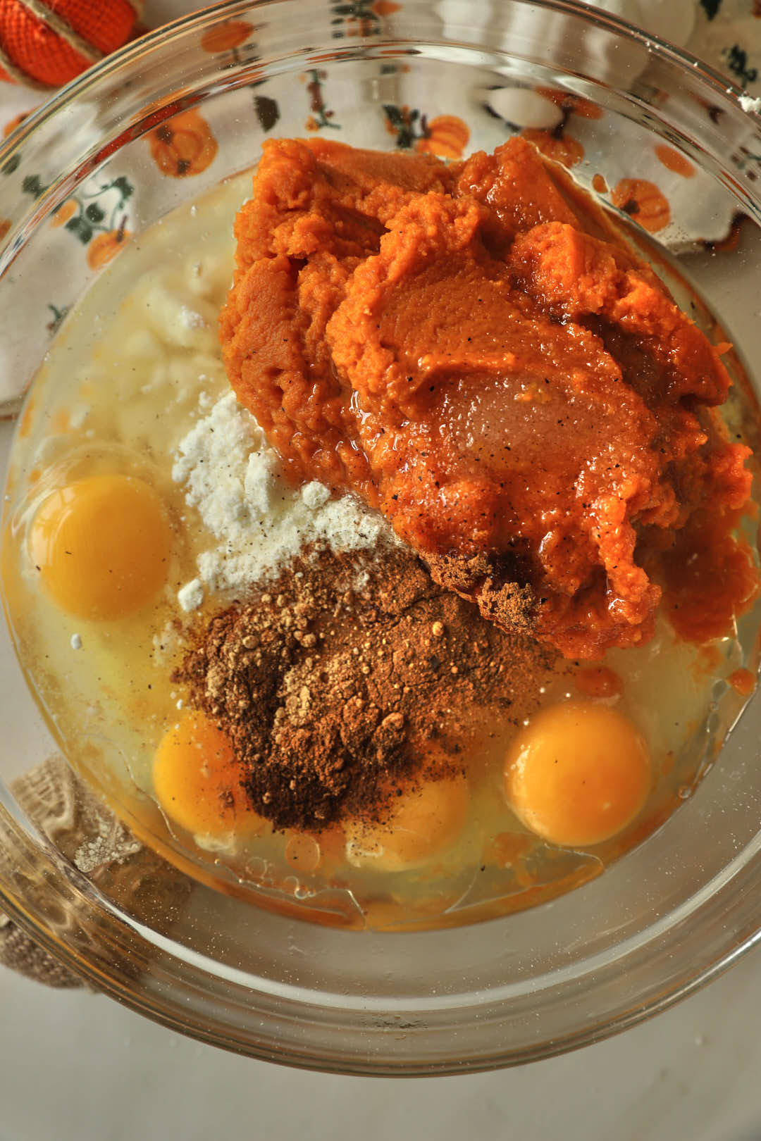 canned pumpkin, eggs, oil, sugar, cake mix, and spices in a glass bowl.