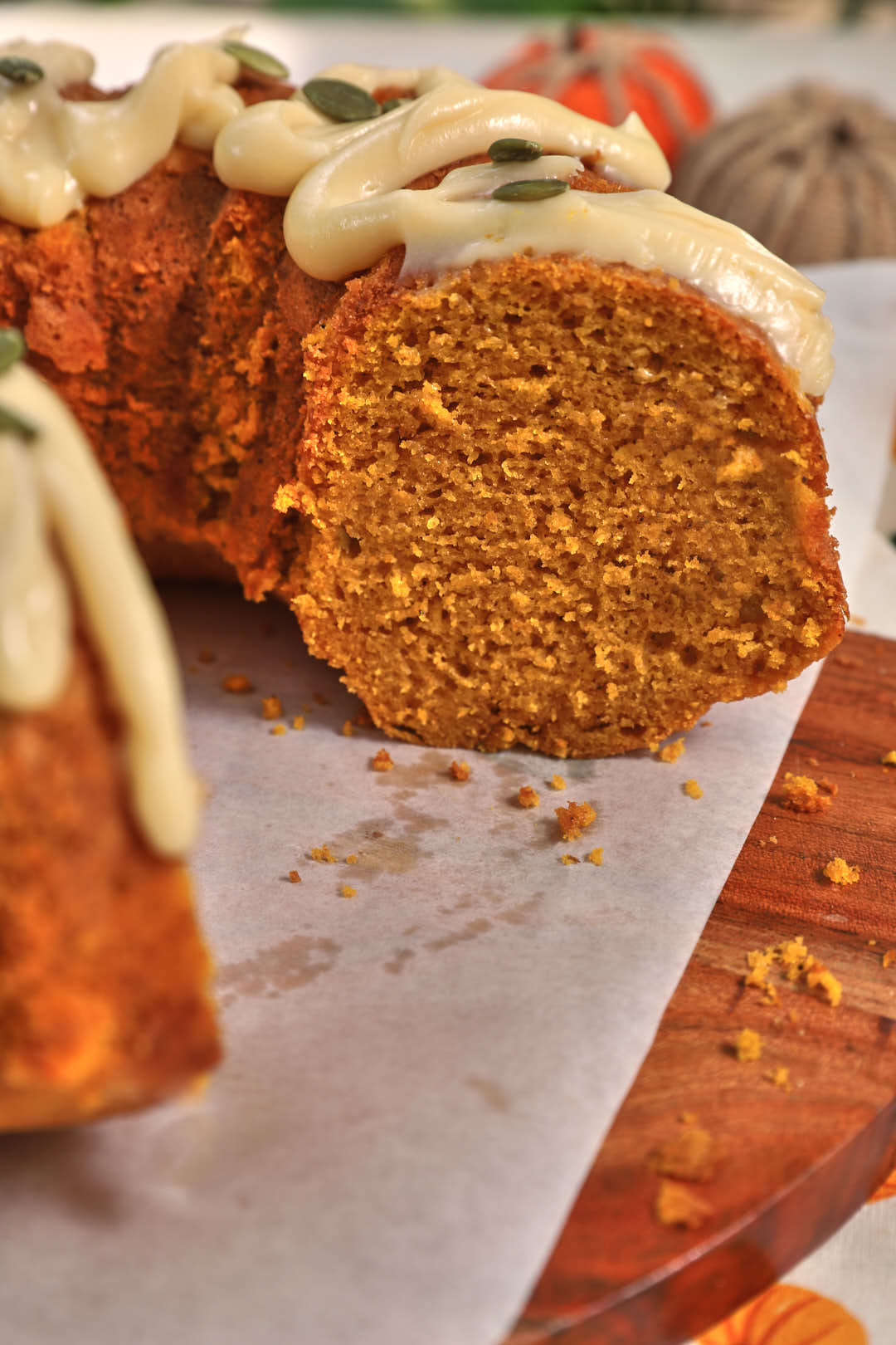 slice of pumpkin bundt cake on parchment paper and on a wooden board.