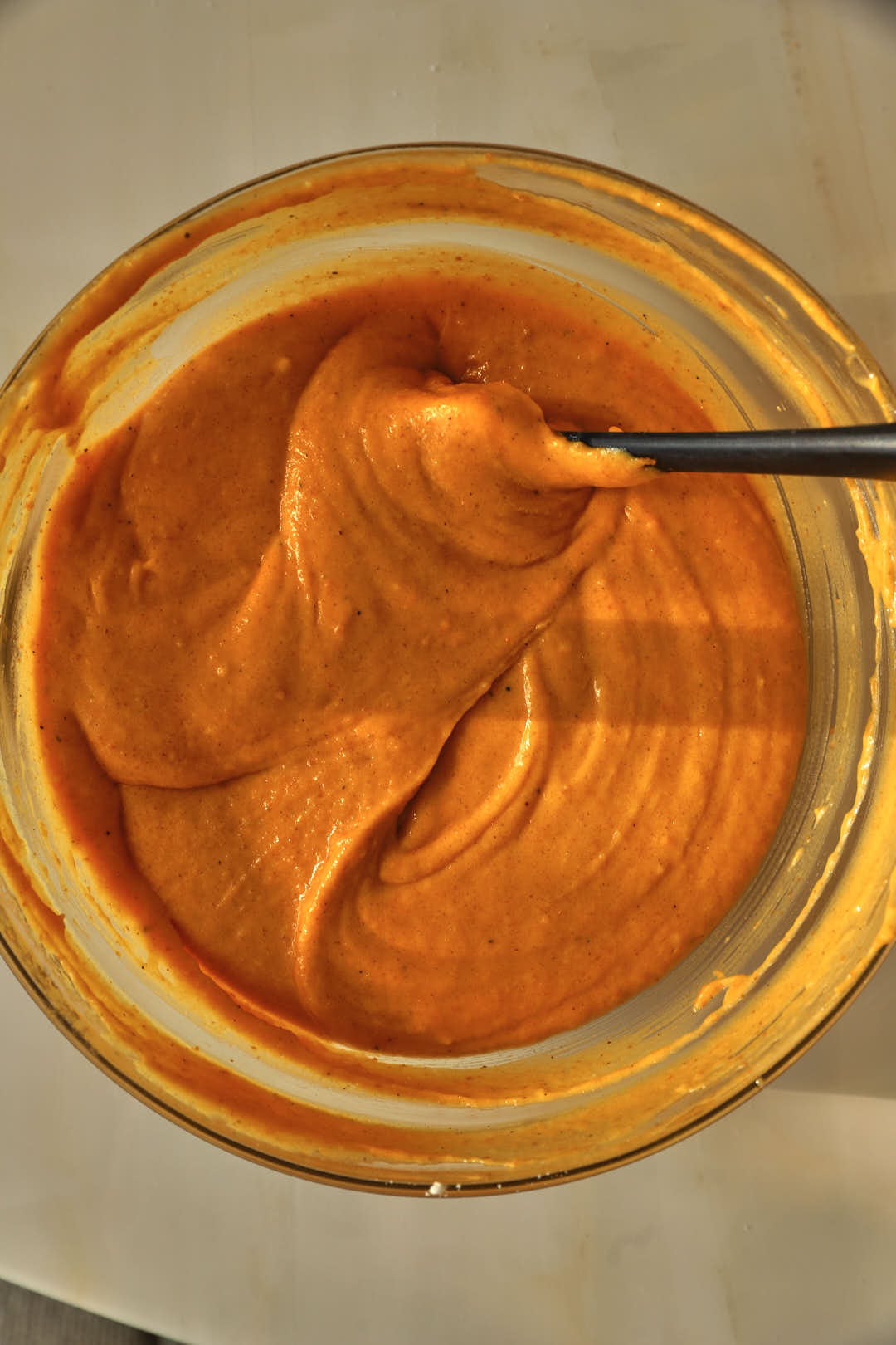 pumpkin cake batter in a glass bowl with a spatula.