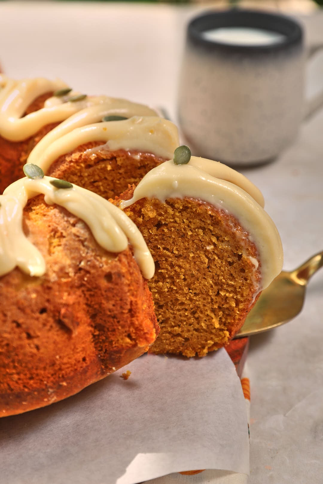 close up slice of pumpkin bundt cake being removed from plate with a golden cake server.