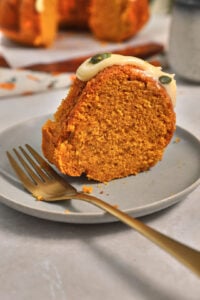 slice of pumpkin bundt cake on a gray plate with a gold fork.