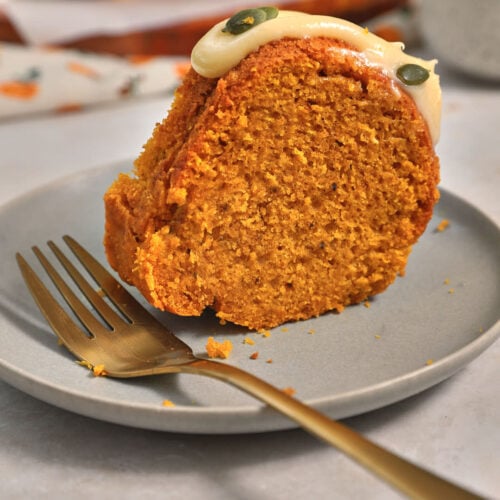 slice of pumpkin bundt cake on a gray plate with a gold fork.