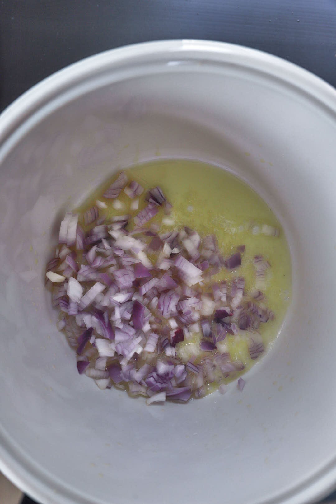 diced red onions in olive oil in a white saucepan.