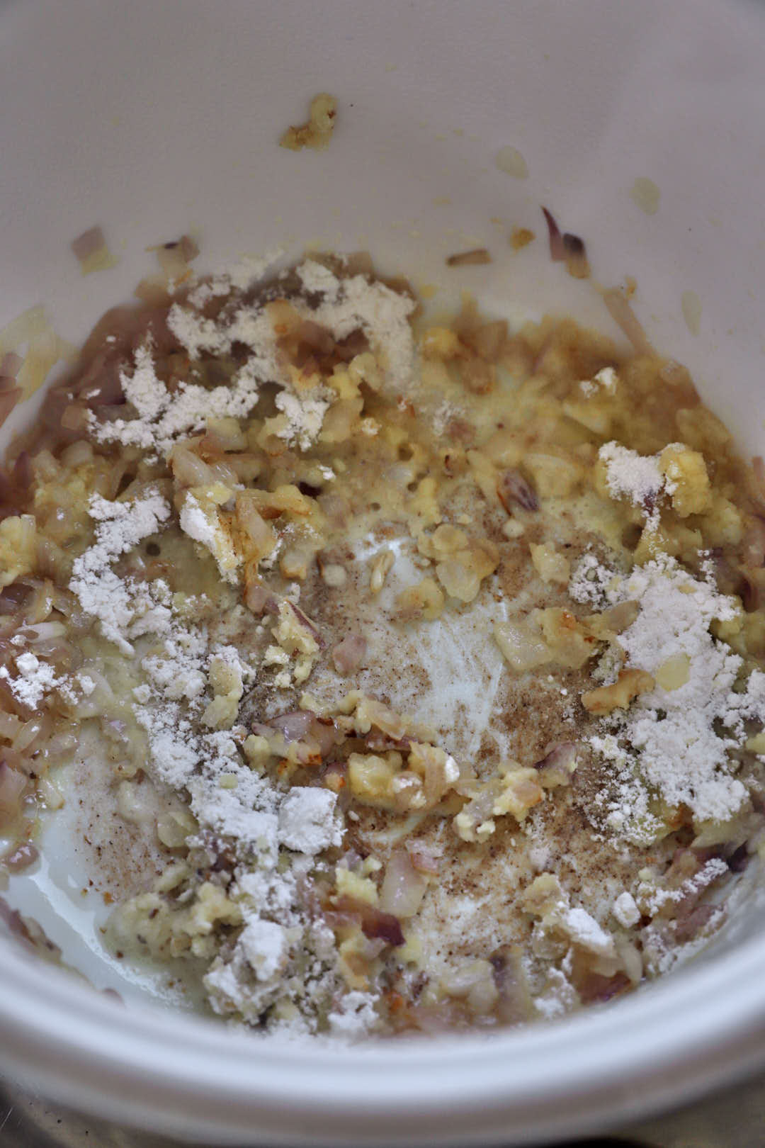 cooked chopped onions in a white saucepan with flour.