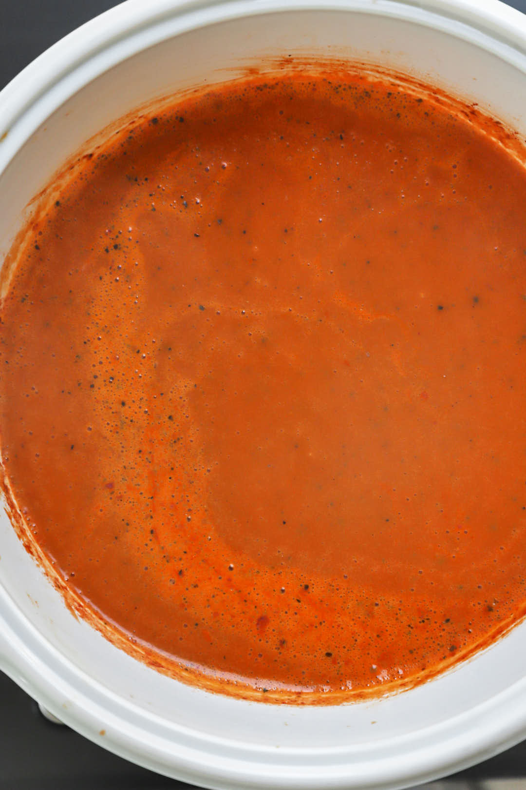 evaporated milk stirred into tomato soup in a white saucepan.