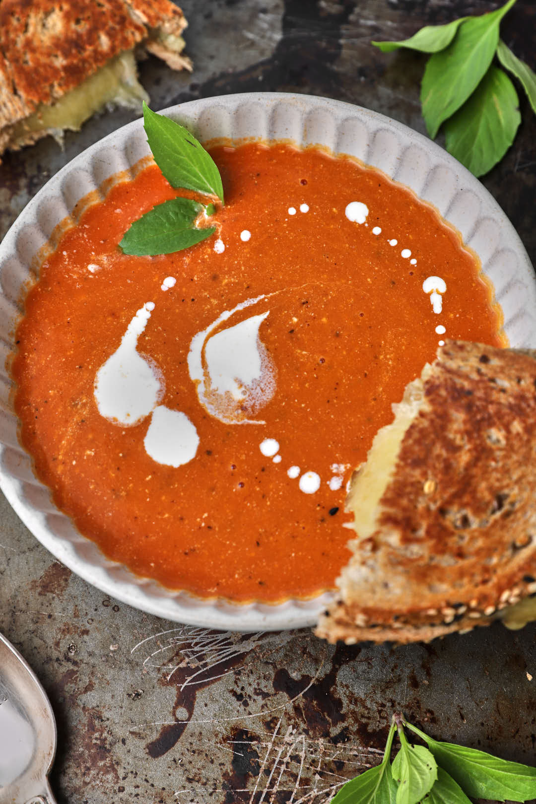 grilled cheese sandwich half resting on a bowl of tomato soup.