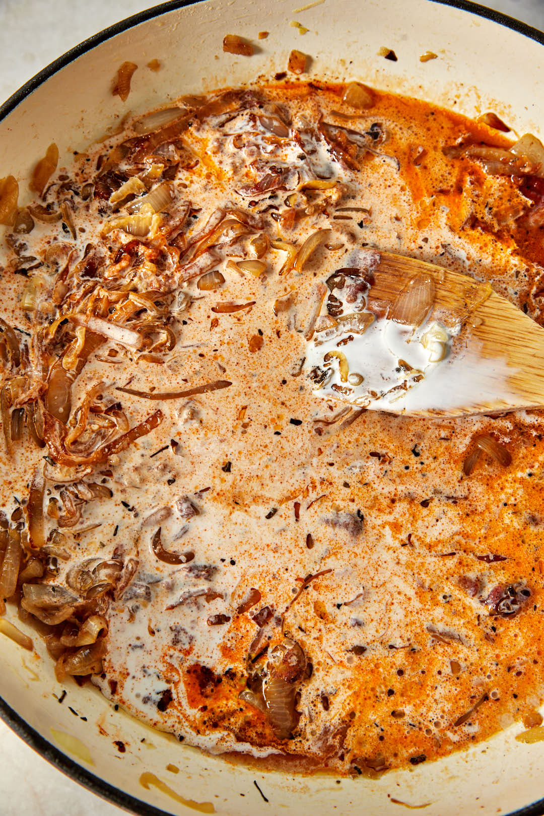 heavy cream and pasta water poured over the caramelized onion and tomato paste mixture in a skillet.