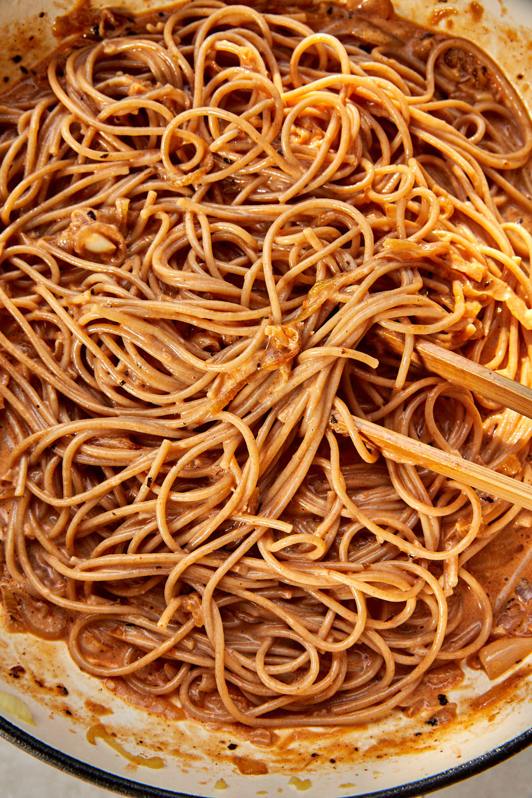 spaghetti tossed in creamy caramelized onion sauce in a skillet.
