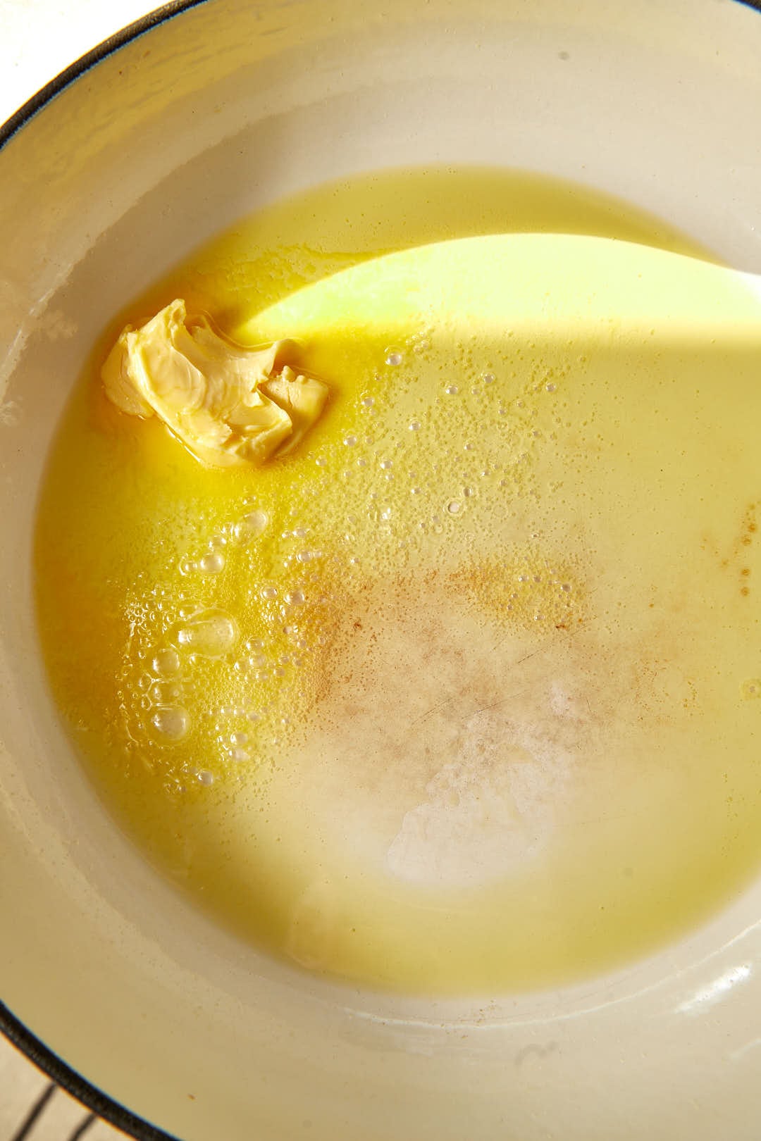 olive oil and butter melting together in a large white skillet.