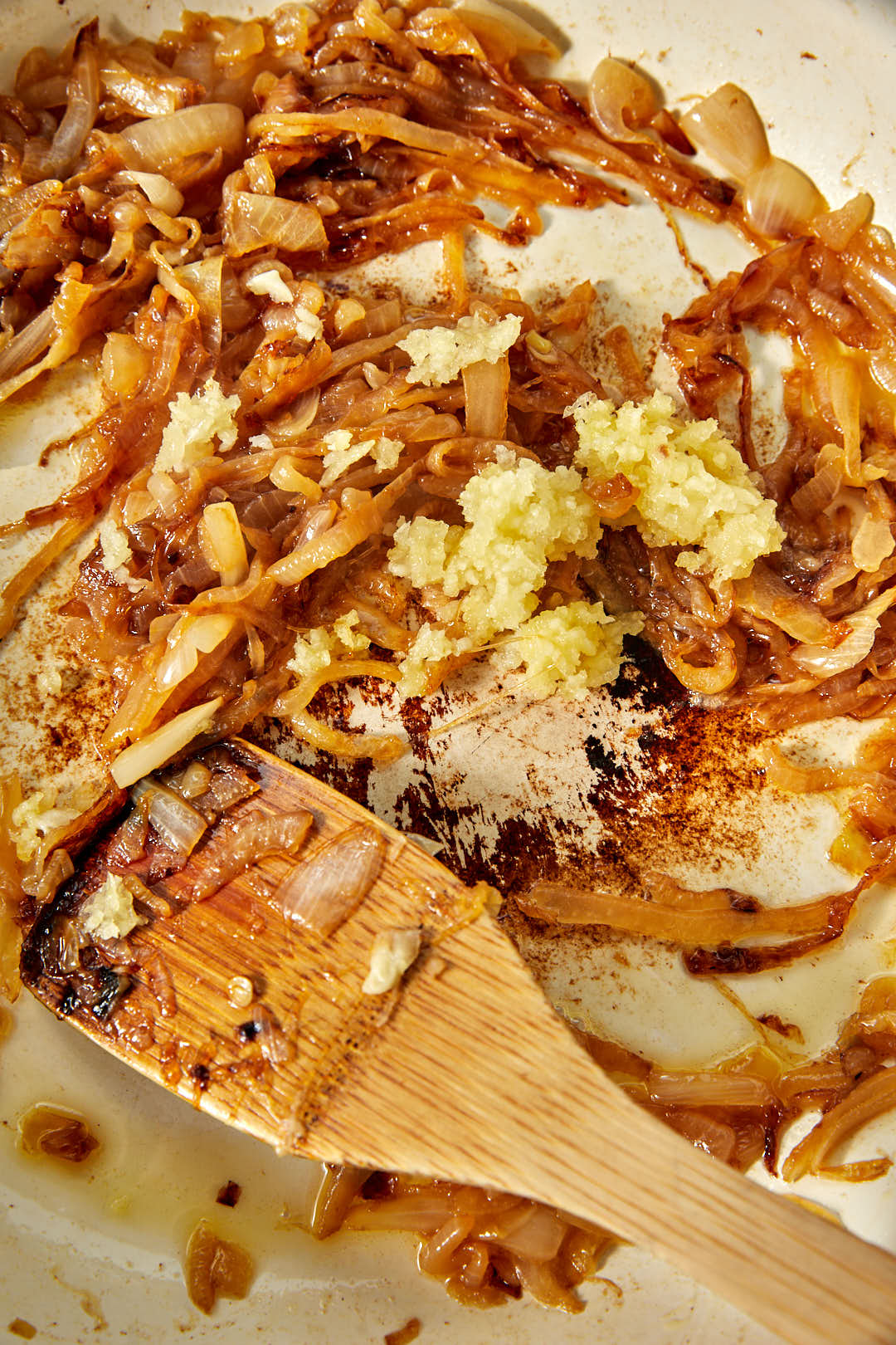 crushed garlic added on top of caramelized onions in a skillet.