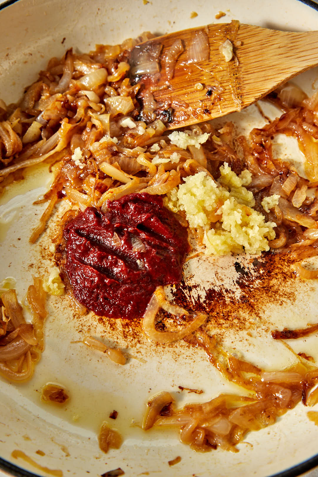 tomato paste and crushed garlic added to caramelized onions in a skillet.