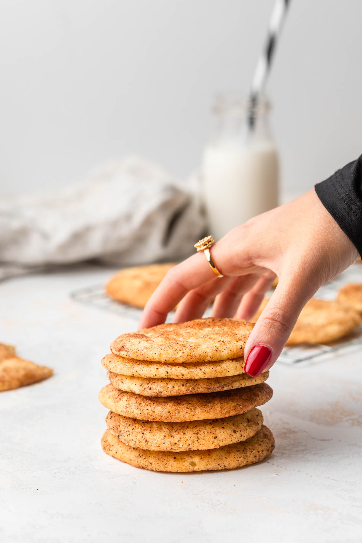 stack of snickerdoodle cookies with a hand reaching for the top one.