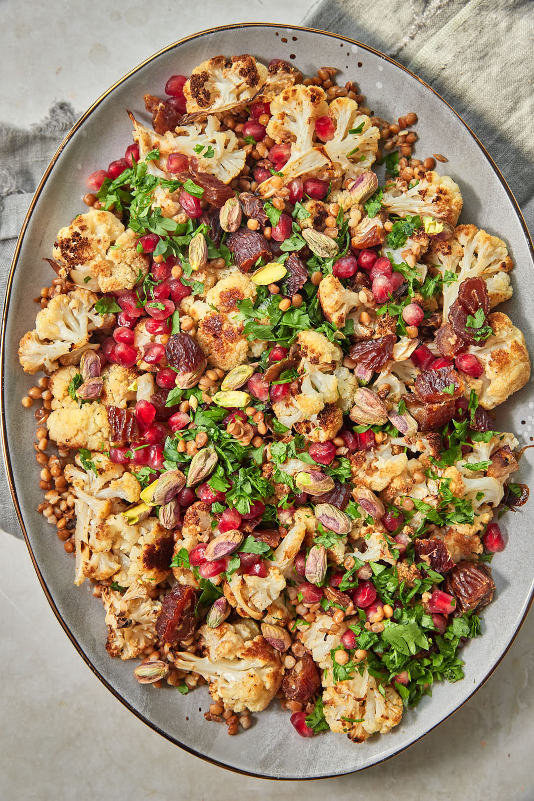 Finished cauliflower lentil salad topped with dates, pomegranate seeds, parsley, and pistachios.