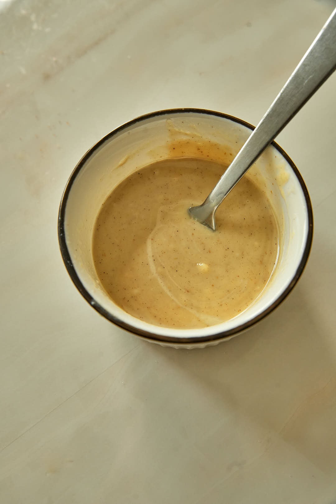 Creamy tahini dressing whisked smooth in a bowl with a spoon