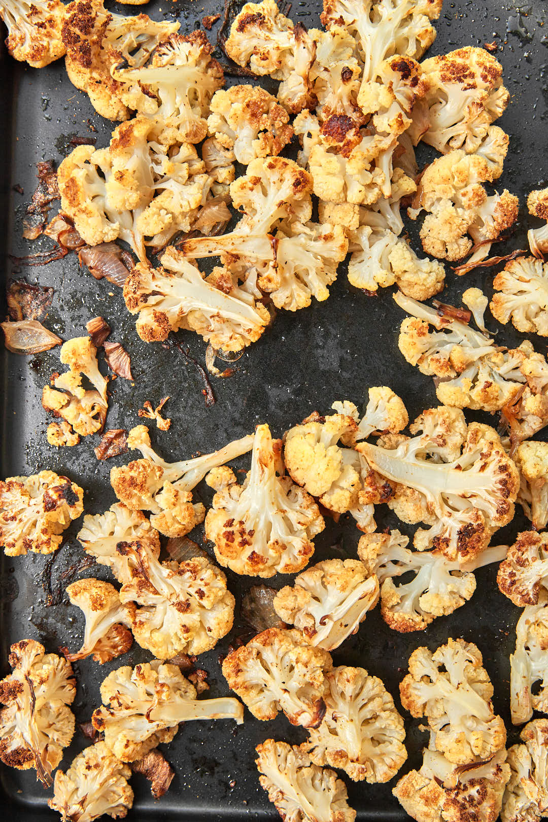 Roasted cauliflower and red onion deeply golden brown on a baking sheet