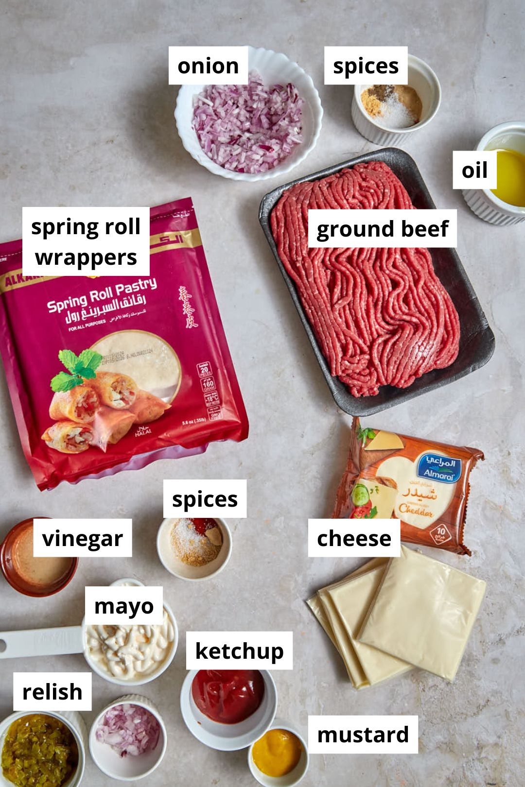 ingredients for cheeseburger spring rolls on a plain background.