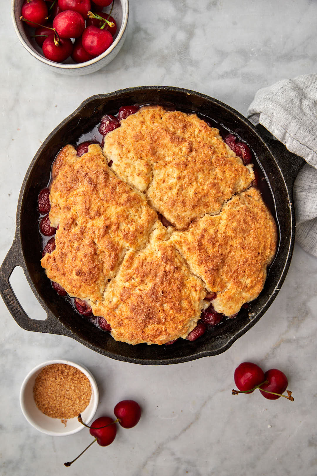 golden brown biscuits on cherry filling in cast iron skillet.