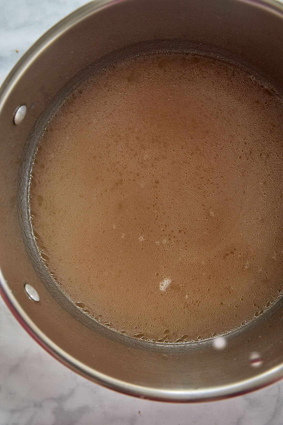 chicken broth in a large saucepan with rice in it.