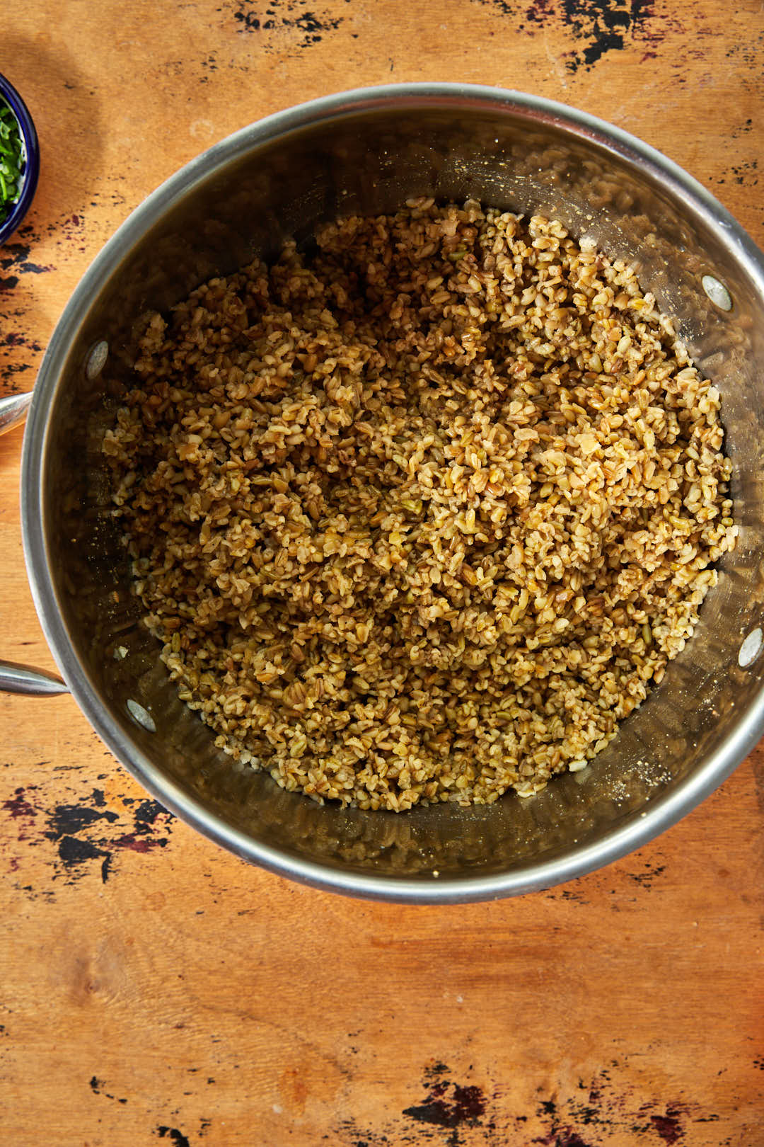 freekeh in saucepan over cooking on a wooden background.