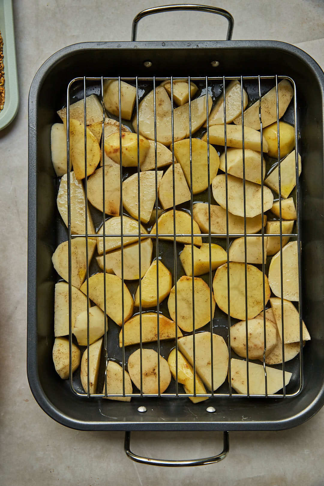 cubed potatoes under a wire rack in a roasting pan.