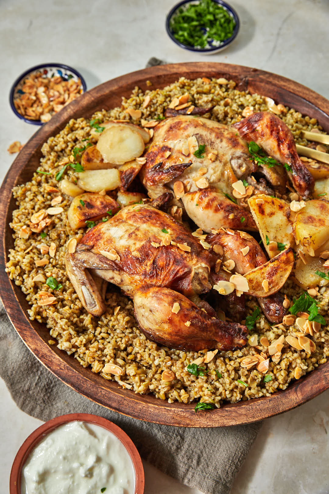 platter of freekeh with whole roasted chicken and potatoes.