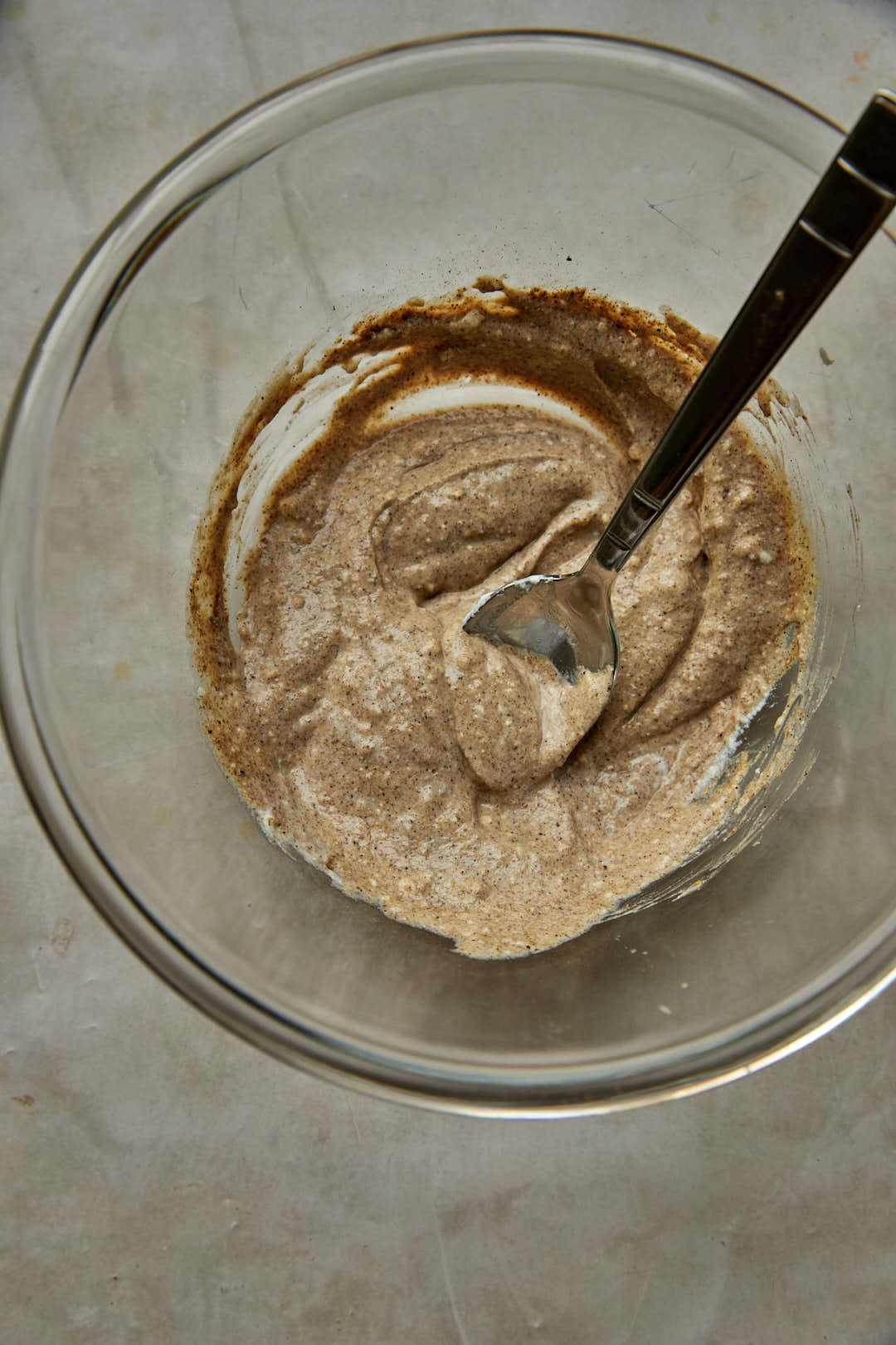 yogurt and spices for a chicken marinade in a glass bowl with a spoon.