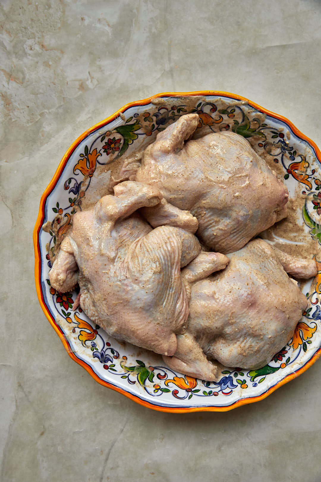 whole chickens that have been smeared with a yogurt marinade in a platter.