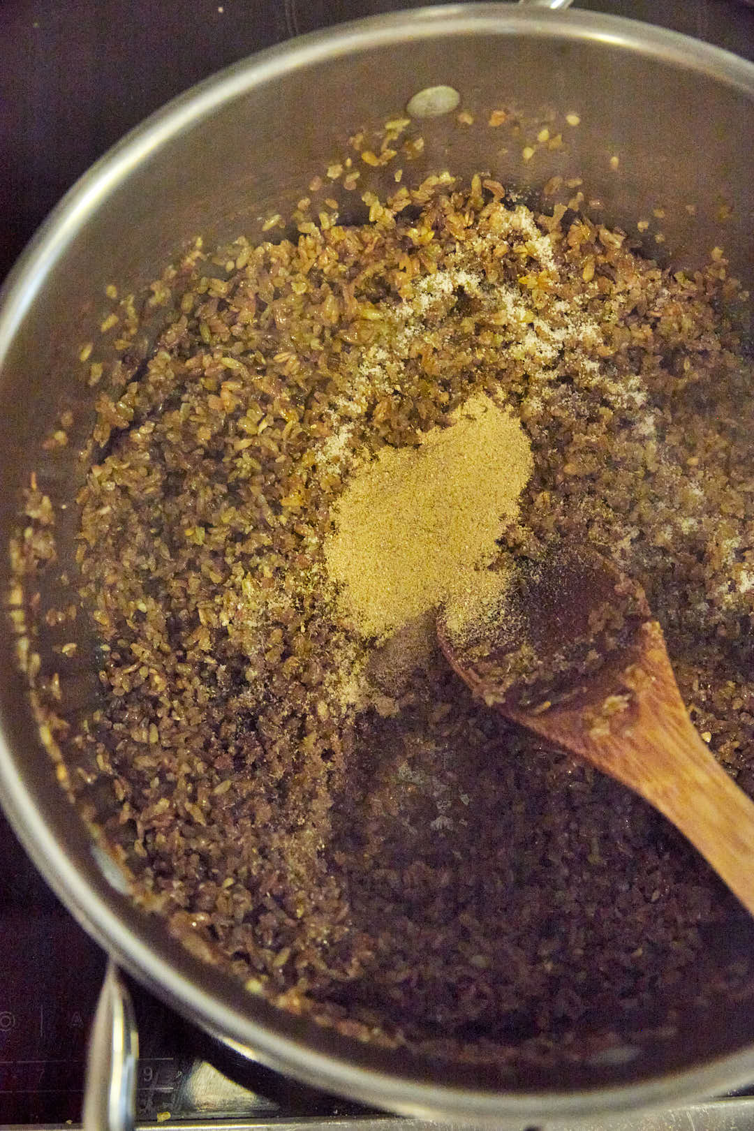 freekeh being toasted in a large pot with spices.