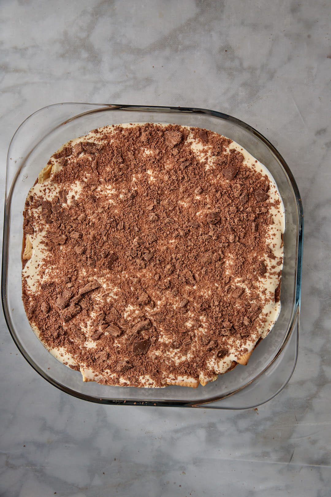 flaked chocolate on a cream mixture in a pyrex pan.